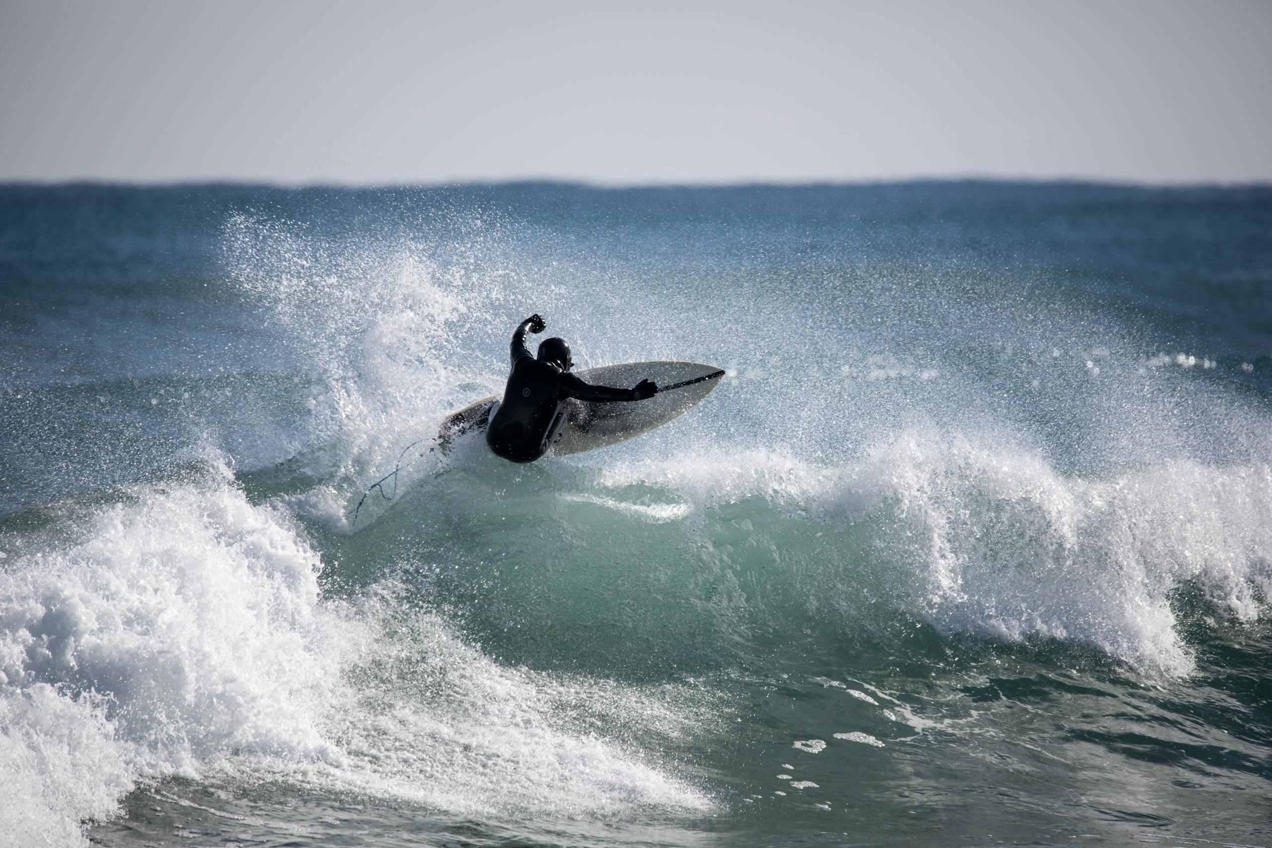 Home Surfer performing a daring maneuver on coastal waves in Yangyang, South Korea.